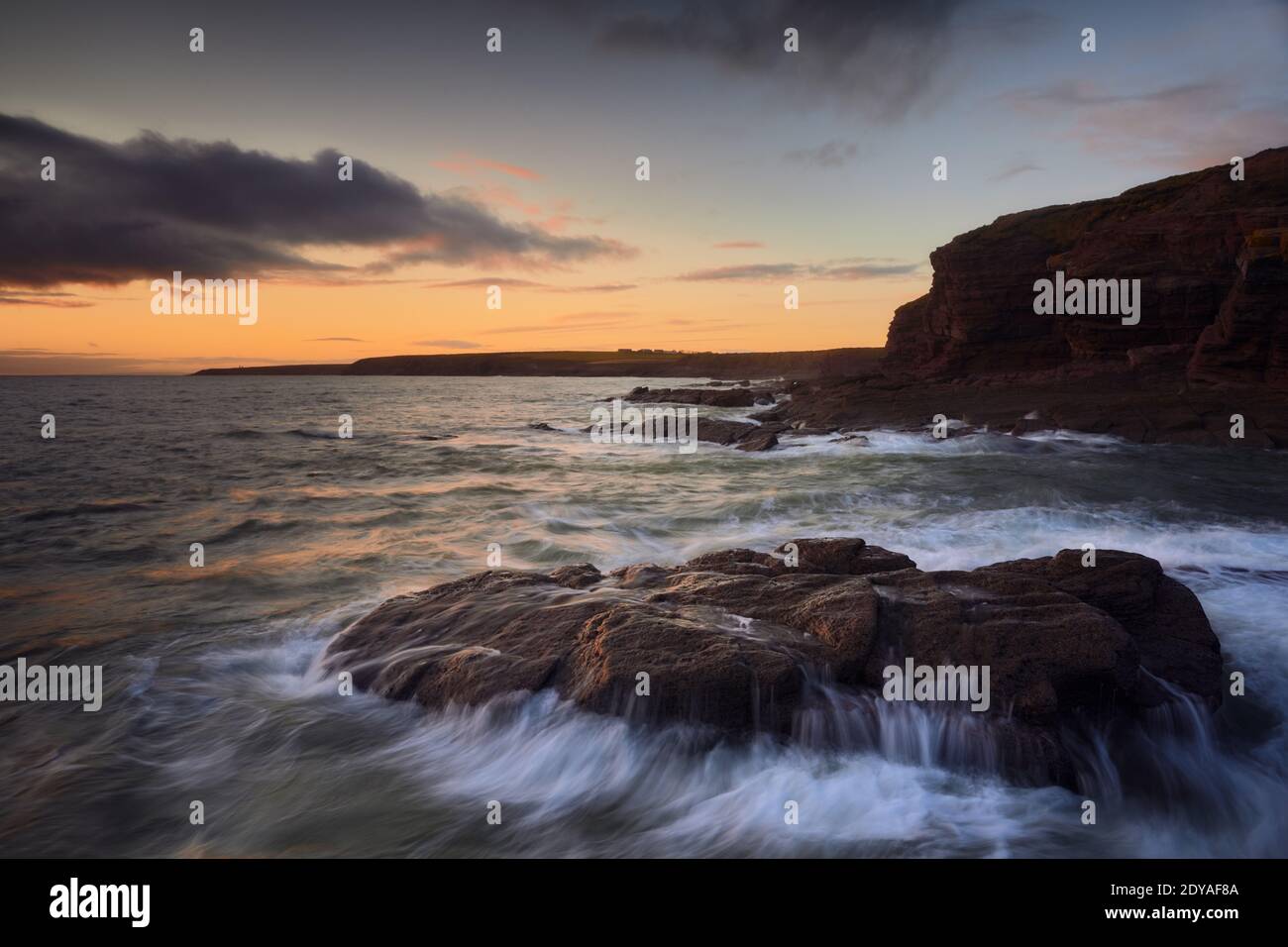 Rochers sur la plage de Cooper Coast, Waterford, Irlande. Coucher de soleil ou lever de soleil avec de l'eau soyeuse. Littoral protégé par l'UNESCO Banque D'Images