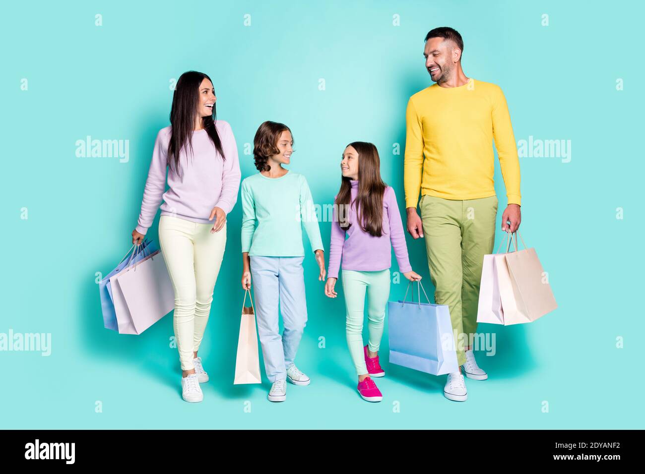 Portrait photo de la famille entière avec les petits enfants tenant des magasins sacs isolés sur fond bleu sarcelle vif Banque D'Images