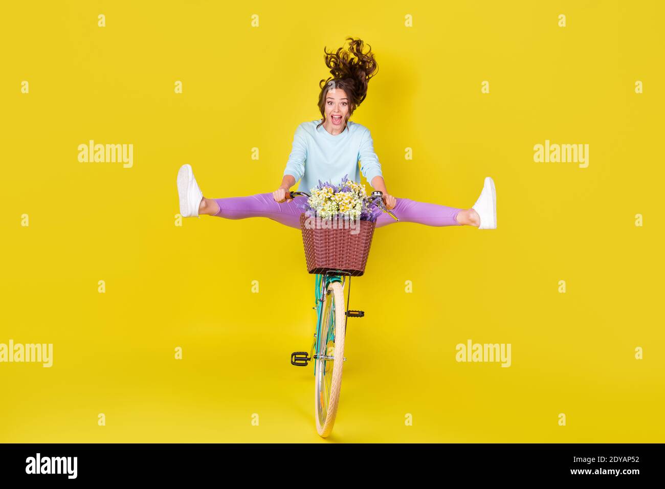 Pleine photo de taille de corps de la jeune fille insane équitation vintage un vélo inhabituel volant de la colline porter des fleurs vent souffle cheveux portez un pantalon violet en pull bleu Banque D'Images