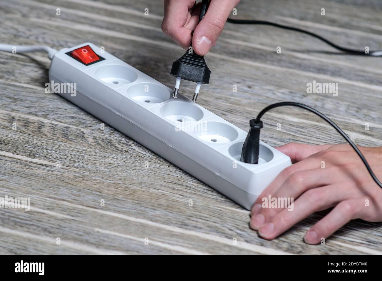 L'hôtesse tient dans sa main une rallonge électrique à l'aide d'un fusible, puis branchez l'appareil sur la prise Banque D'Images