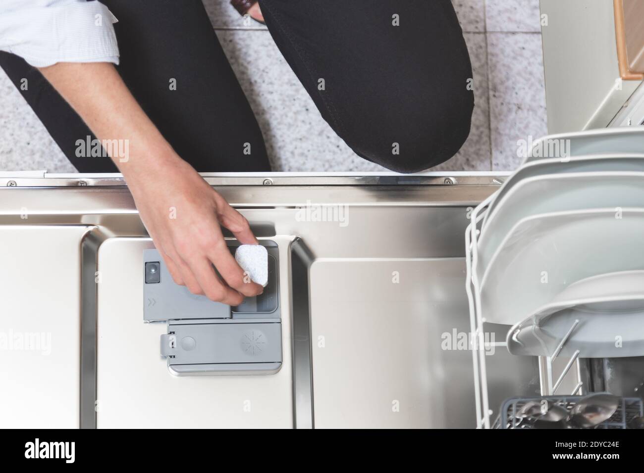 Gros plan de la personne mettant à la main le savon pour lave-vaisselle dans la boîte de détergent pour lave-vaisselle. Concept de travaux ménagers. Banque D'Images
