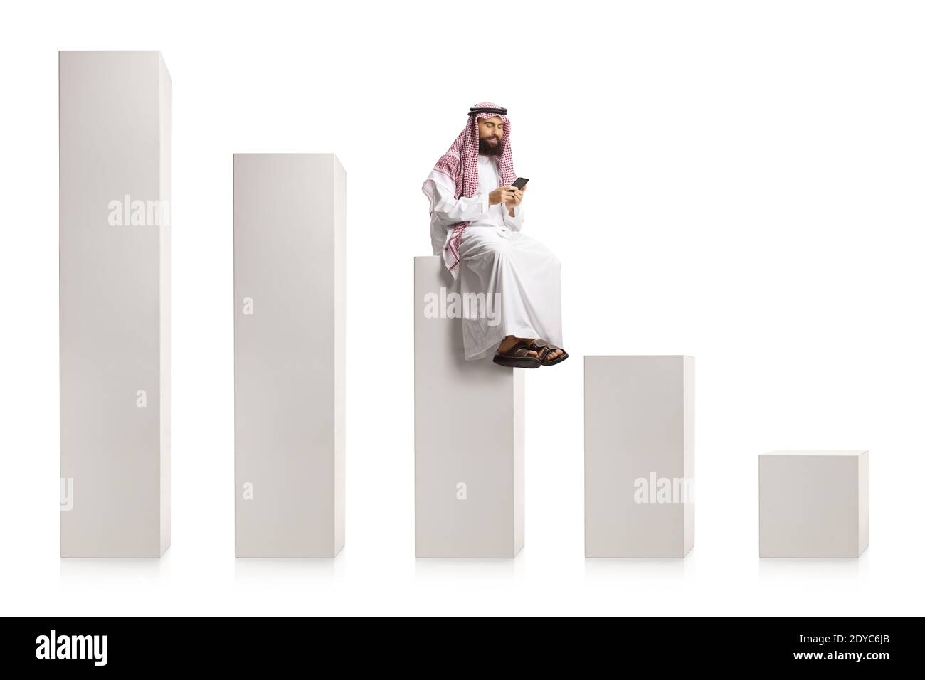 Homme arabe utilisant un smartphone et assis sur un milieu colonne blanche s'élevant de bas à haut isolée sur fond blanc Banque D'Images