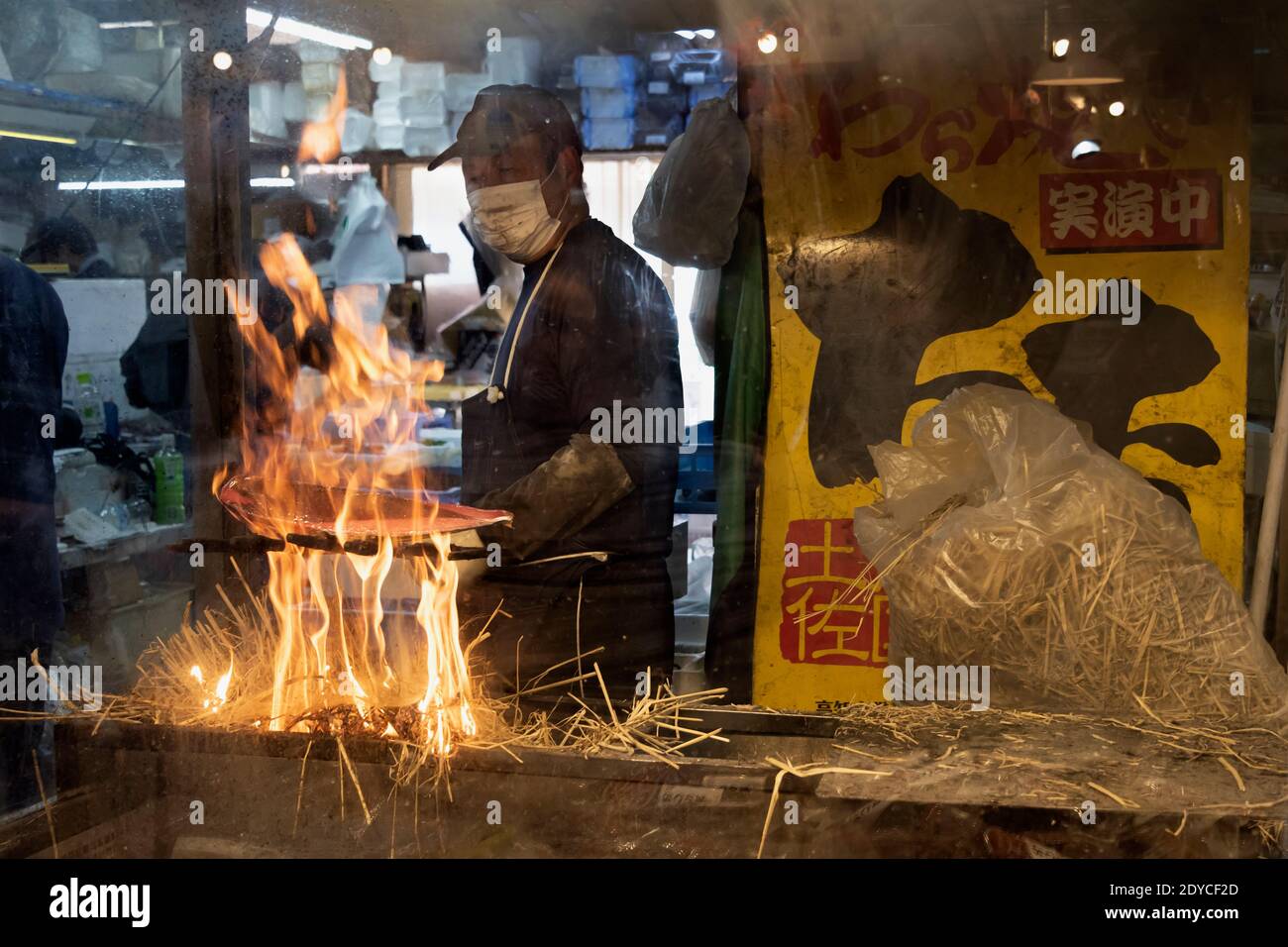 Homme cuisant katsuo no tataki (bonite poêlée) sur une flamme de paille ouverte, Kochi, Japon Banque D'Images