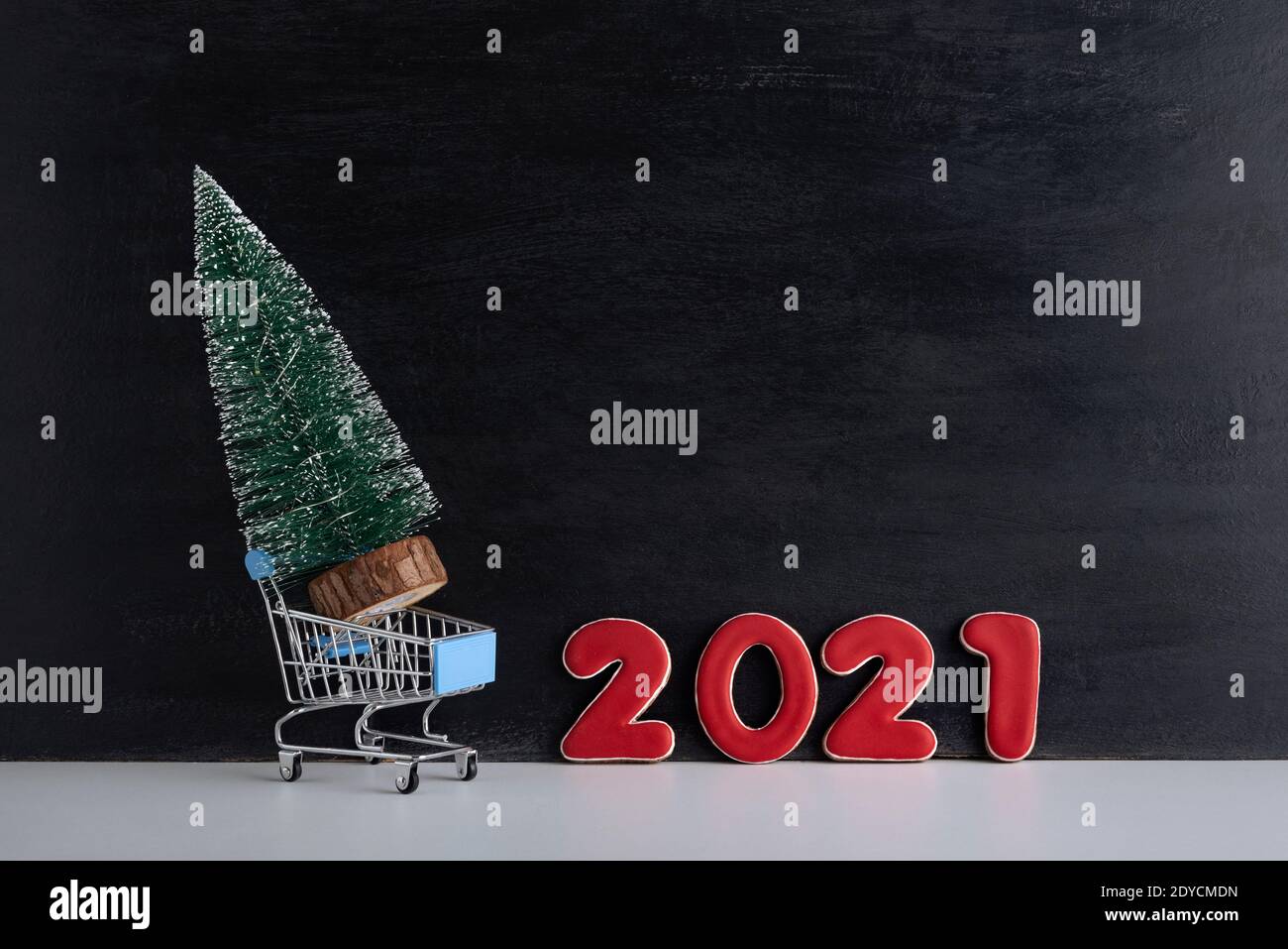 Arbre de Noël miniature dans un chariot contre le fond de l'inscription 2021. Achat et location d'arbres de Noël. Banque D'Images