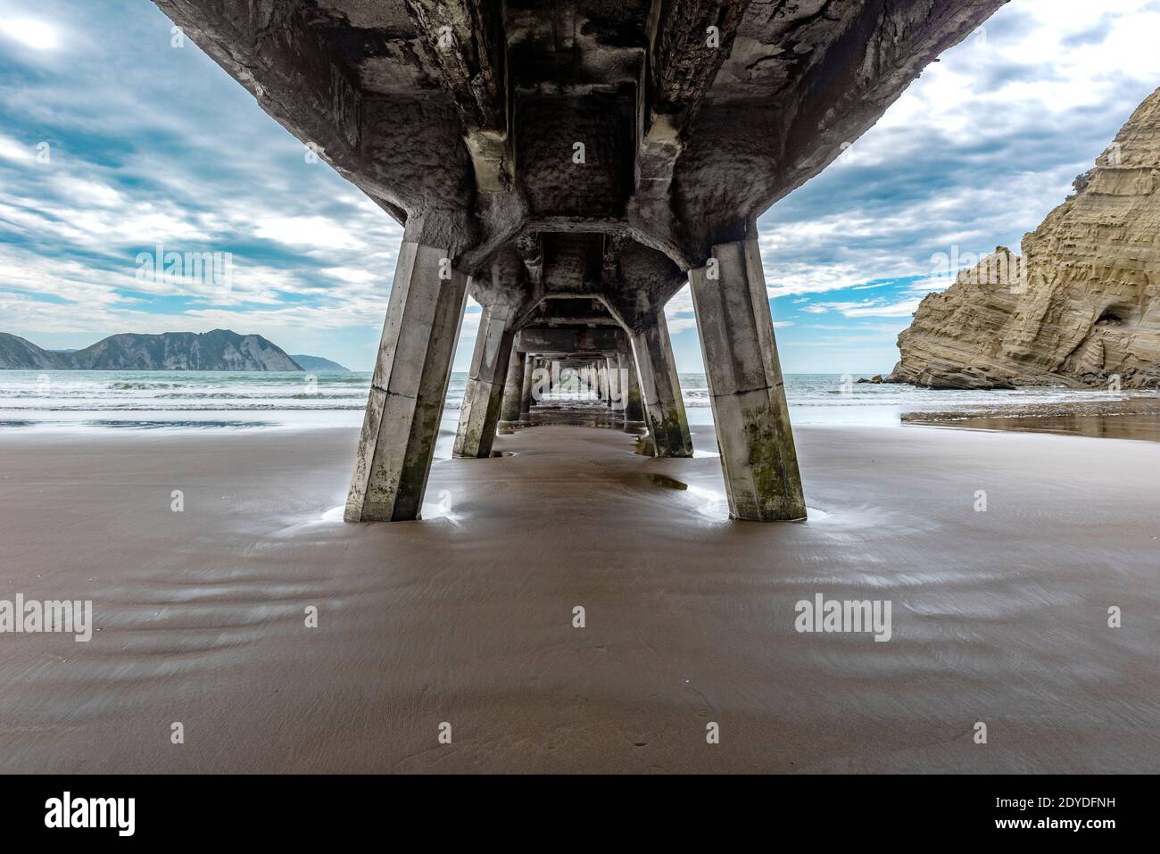 Tolaga Bay Wharf s'étendant dans la mer sous un ciel nuageux Ciel en Nouvelle-Zélande Banque D'Images