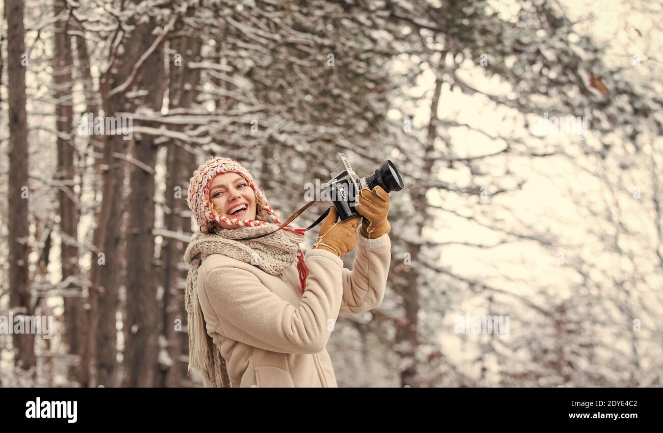 femme tenant un appareil photo. prendre une photo en forêt d'hiver. Photographe photographiant le jour de l'hiver enneigé. Femme heureuse vêtements chauds mode. Vacances en hiver. Voyageur élégant. Banque D'Images