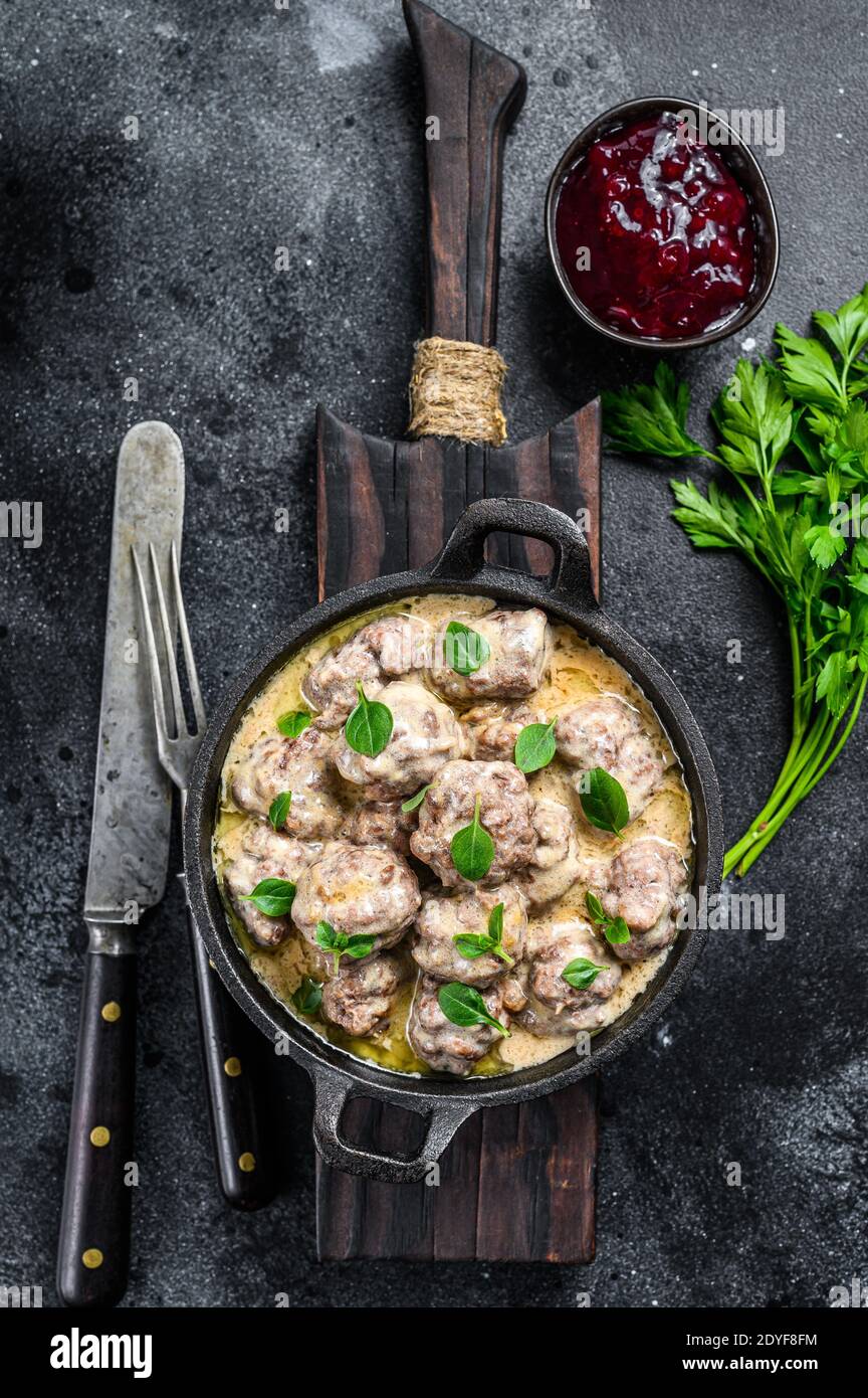Boulettes de viande suédoises à la sauce aux baies de lingonis dans une poêle. Fond noir. Vue de dessus Banque D'Images