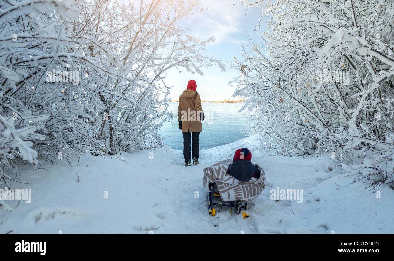 Une Mere Avec Un Enfant Marche Un Matin D Hiver Glacial Le Jour Du Soleil Bebe Enveloppe Dans Une Couverture Sur Un Traineau Photo Stock Alamy