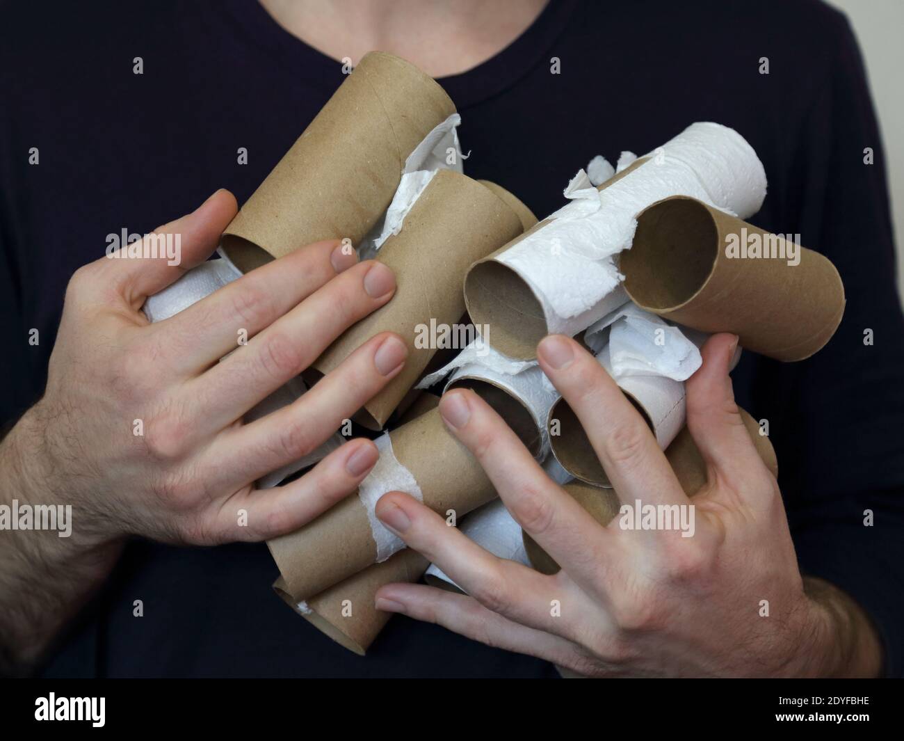 Une paire de mains mâles tient beaucoup de papier toilette en carton vide TP roule vers le haut de près. Banque D'Images