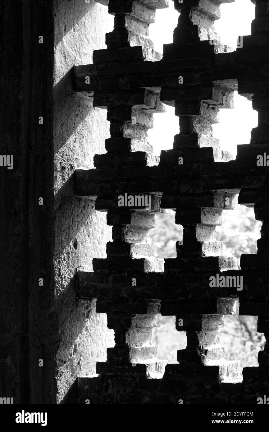 Lumière qui brille à travers les ouvertures dans le mur de briques Banque D'Images