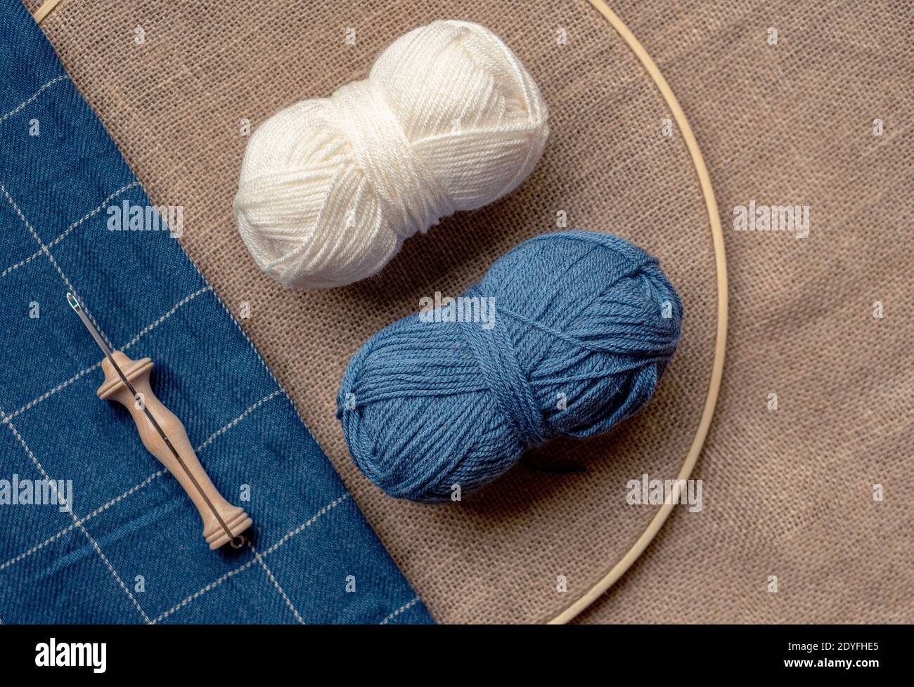 Composition en diagonale avec espace de copie de deux balles de laine et une aiguille poinçonneuse en bois sur un tissu en toile de jute et une couverture bleue Banque D'Images