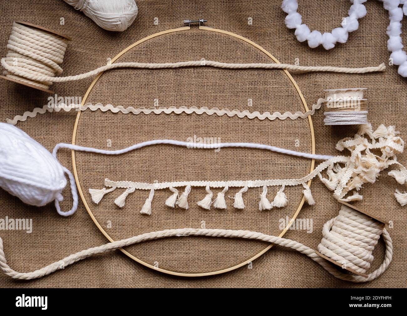 Plusieurs types différents de rubans, de garnitures et de cordes dans des tons naturels sur un tissu de toile dans un cerceau de broderie de bambous Banque D'Images