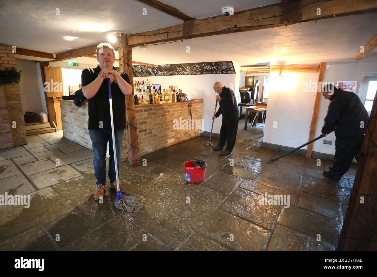 Alconbury Weston, Royaume-Uni. 24 décembre 2020. David Senior, propriétaire du White Hart, s'arrose de l'eau de crue, espérant ouvrir prêt pour le déjeuner aujourd'hui car il est complet. L'eau de crue dans le village d'Alconbury Weston, car de fortes pluies ont chuté pendant des heures, provoquant l'éclatement du ruisseau sur les rives, inondant les routes et les maisons. Elle a atteint un nouveau record, plus élevé que son précédent record de novembre 2012. Crédit : Paul Marriott/Alay Live News Banque D'Images