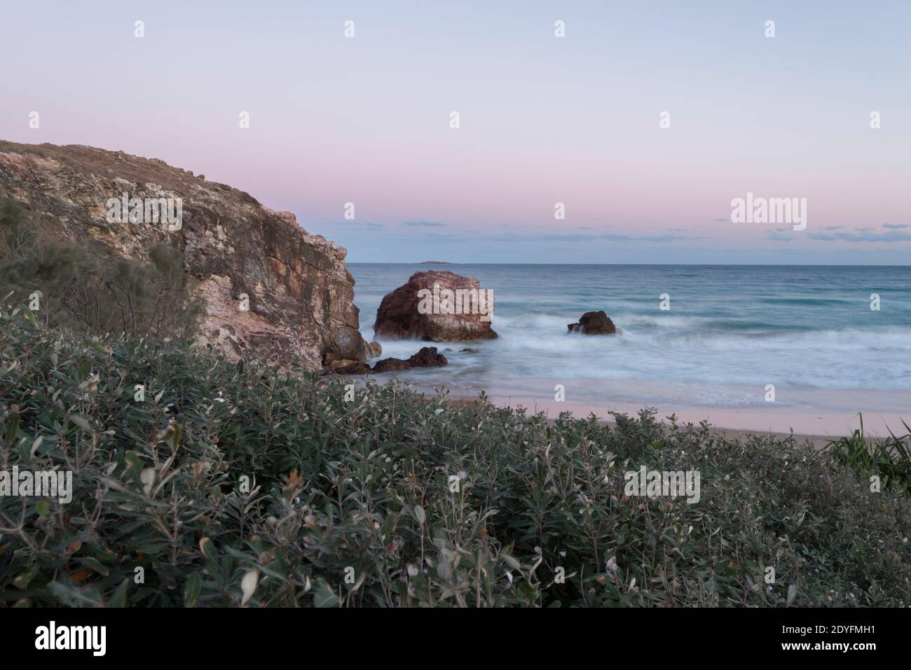 Paysage côtier avec falaises rocheuses et ciel pastel, scène typique de la côte est de l'Australie. Banque D'Images