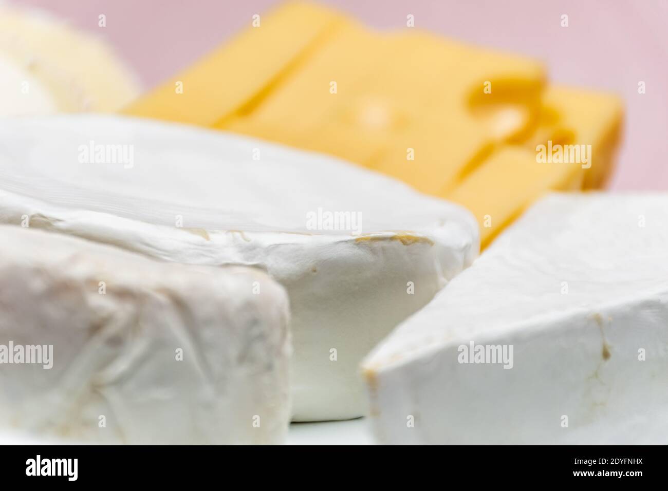 Tableau d'assortiment de fromages. Fromage de chèvre, fromage de vache, fromage de brebis. Fruits et noix de la forêt. Arrière-plan avec un tissu rose, non mis au point Banque D'Images