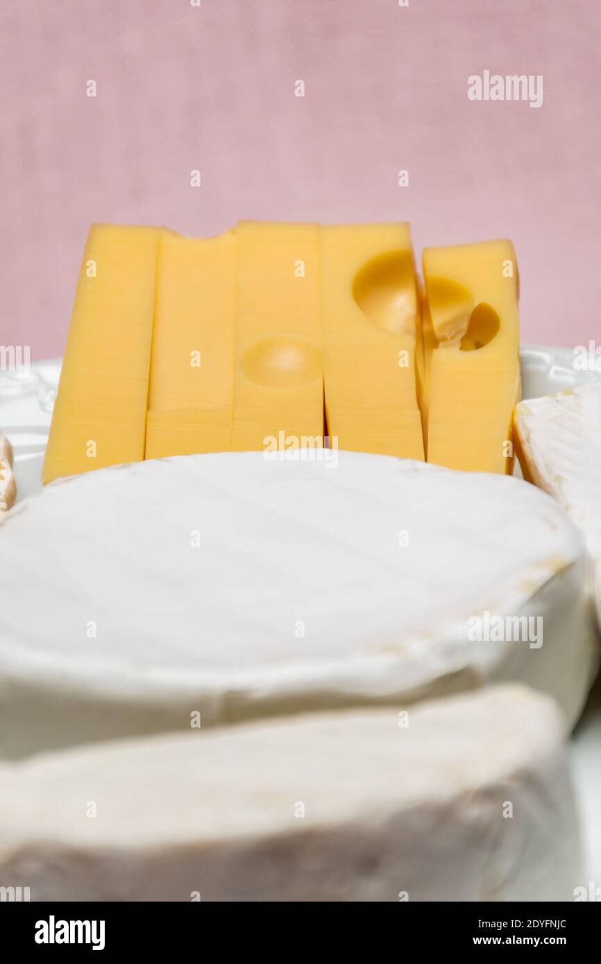 Tableau d'assortiment de fromages. Fromage de chèvre, fromage de vache, fromage de brebis. Fruits et noix de la forêt. Arrière-plan avec un tissu rose, non mis au point Banque D'Images
