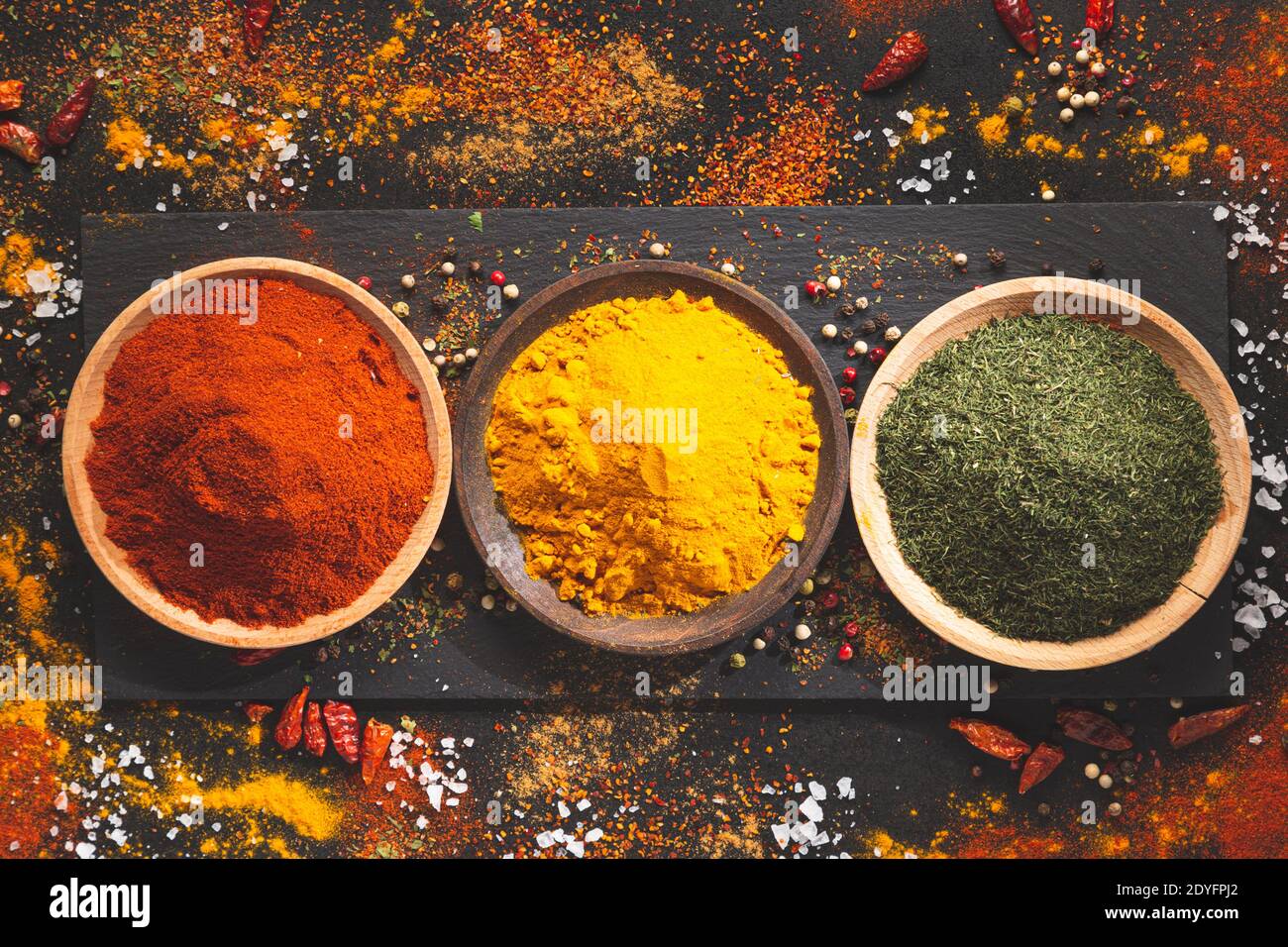 Différentes épices sur fond noir, vue du dessus. Condiments de cuisine concept. Banque D'Images