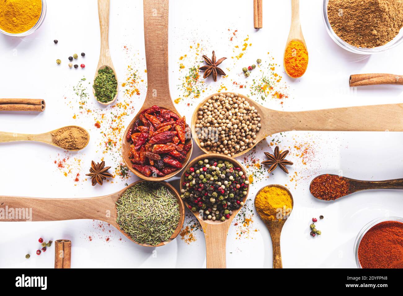 Variété d'épices et d'herbes dans des cuillères et des bols sur fond blanc. Vue de dessus. Ingrédients de cuisine et condiments concept. Banque D'Images