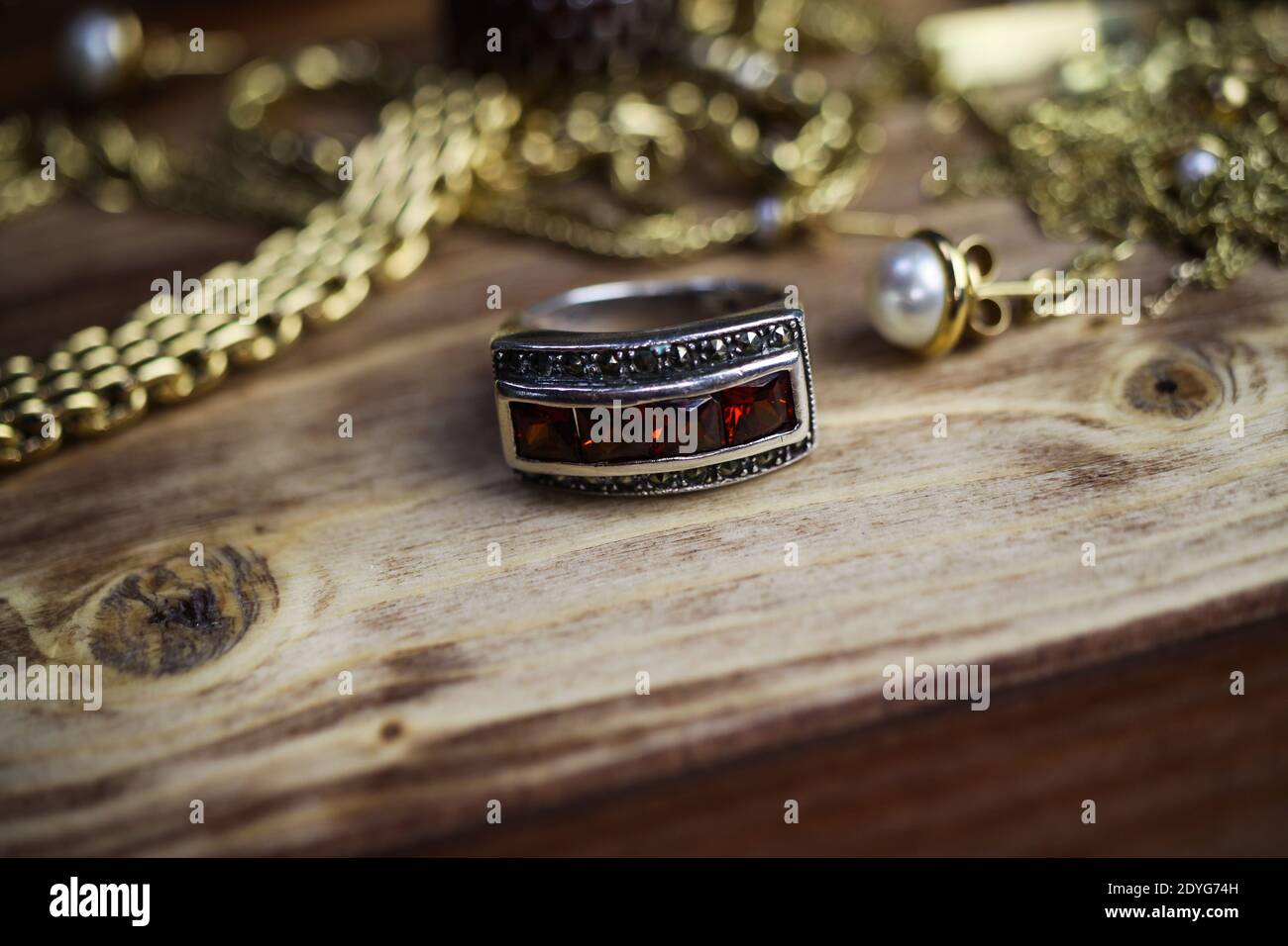 Gros plan isolé groupe or précieux bijoux chaînes et bracelets avec anneau  en pierre rubis argenté sur table en bois Photo Stock - Alamy