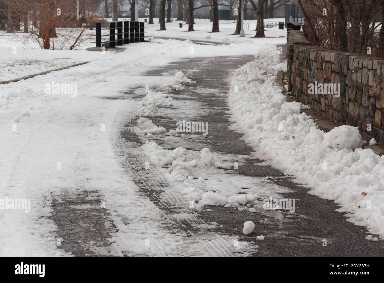 Une route enneigée avec des pneus trapèsla neige à Inwood Hill Park, New York Banque D'Images