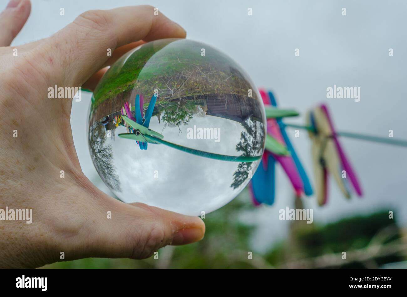 Se fixe sur une ligne de lavage dans un jardin vu à l'envers dans une boule de cristal de verre qui agit comme une lentille et provoque la réfraction. Banque D'Images
