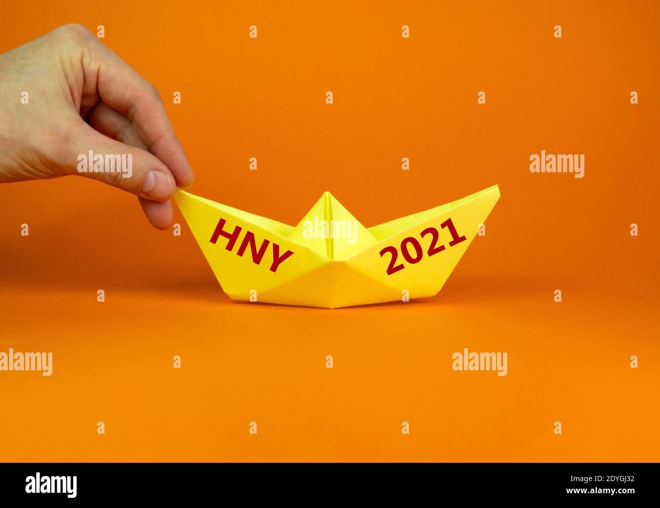 2021 symbole HNY. Image de l'homme d'affaires poussant le papier fait l'origami bateau vers l'avant avec des mots 2021 HNY - Bonne Année. Sur fond orange avec copie s. Banque D'Images
