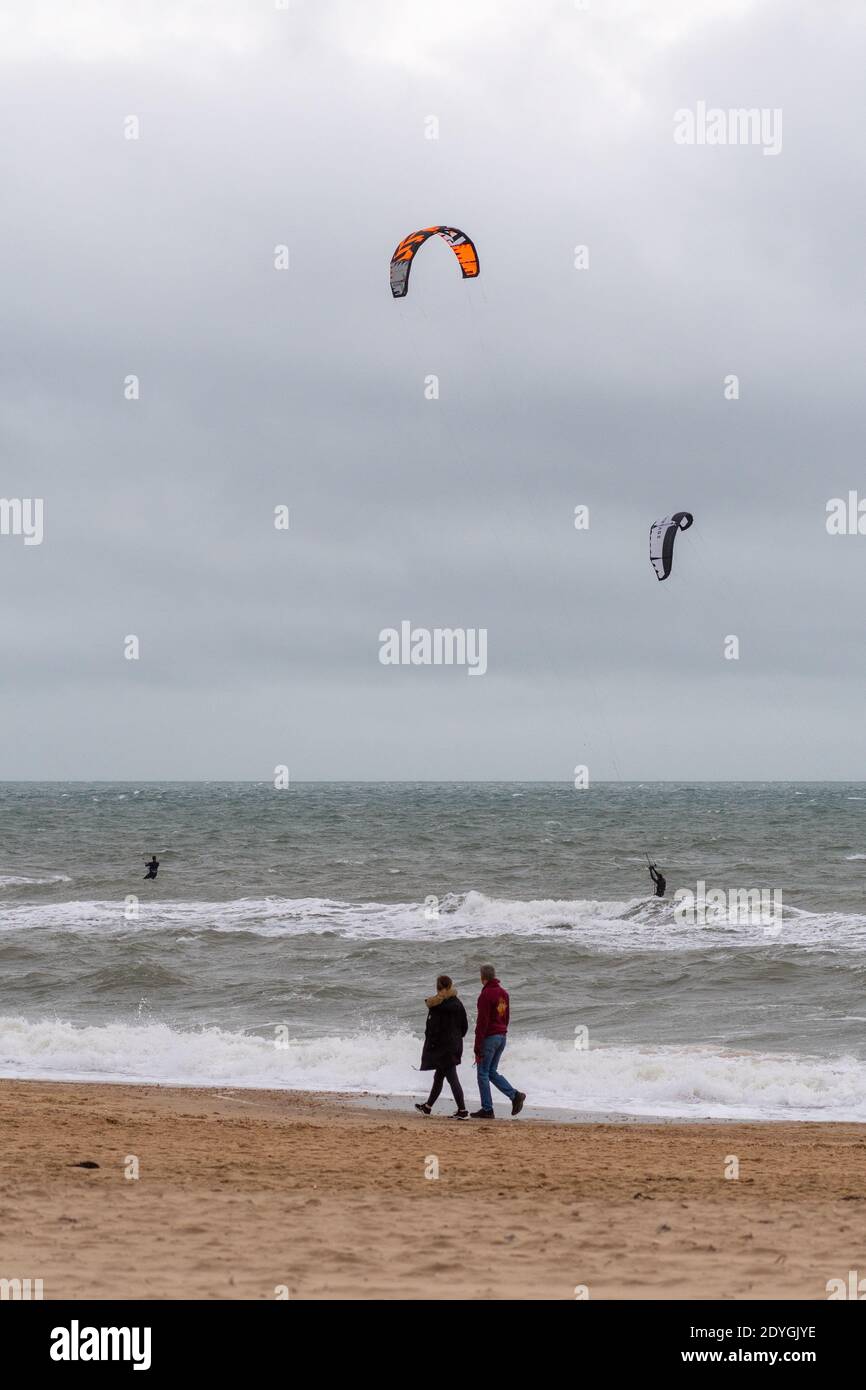 Kite-surfeurs et marcheurs sur la plage à Storm Bella, Boscombe, Bournemouth, Dorset, Royaume-Uni, 26th décembre 2020, le lendemain de Noël, le temps de l'après-midi. Augmentation de la force du vent sur la côte sud de l'Angleterre avec l'approche de Storm Bella, la deuxième tempête nommée de l'hiver. Des vents destructeurs allant jusqu'à 80mph et des pluies torrentielles sont attendus. Banque D'Images
