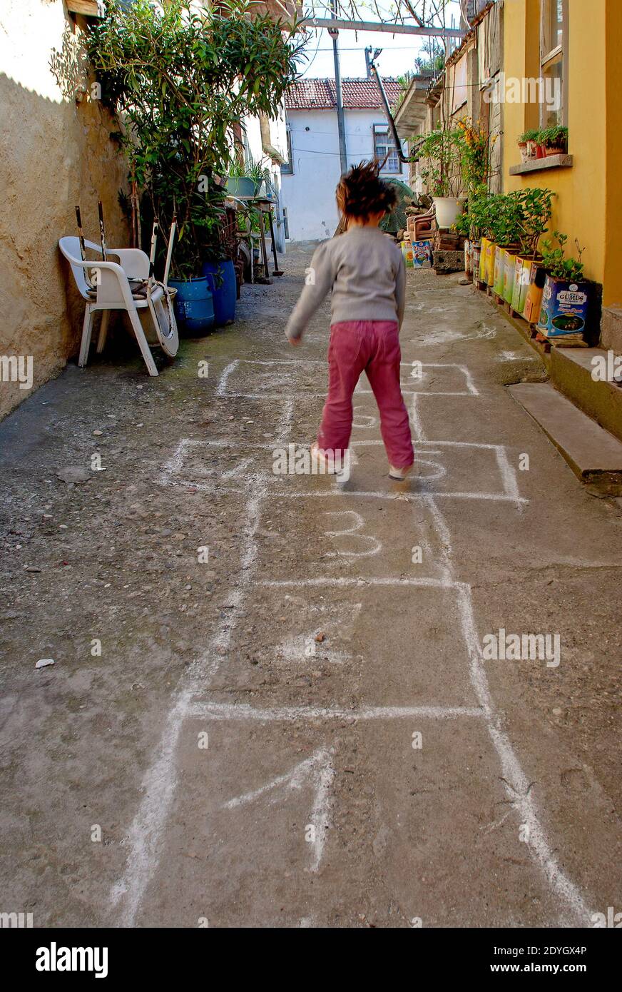 Jeux pour enfants de la rue dans des classiques. Petite fille jouant le  hopscotch dessiné avec de la craie sur le sol Photo Stock - Alamy