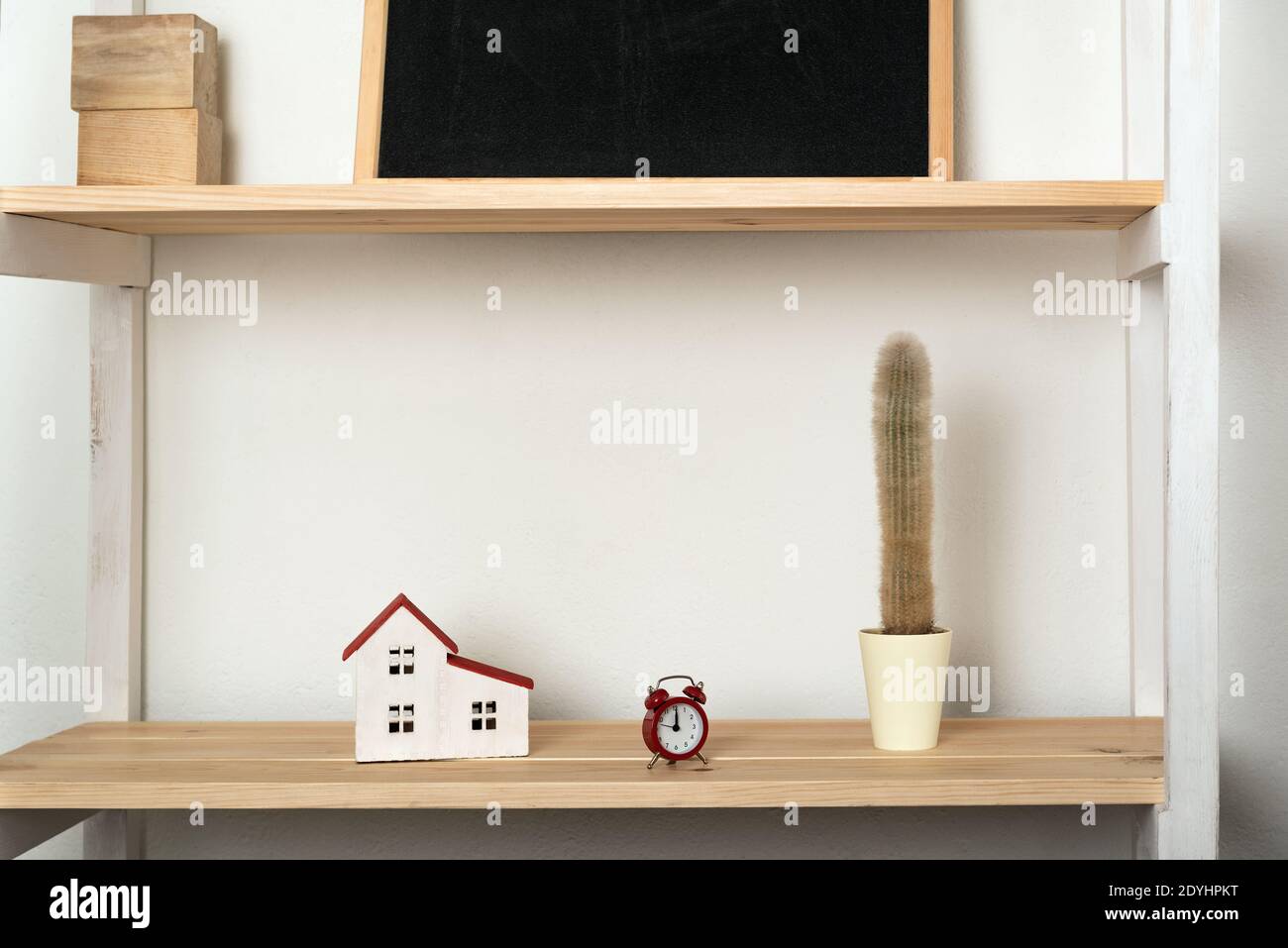 Cactus, maison modèle et réveil rétro sur étagère en bois. Décoration intérieure dans des couleurs claires. Banque D'Images
