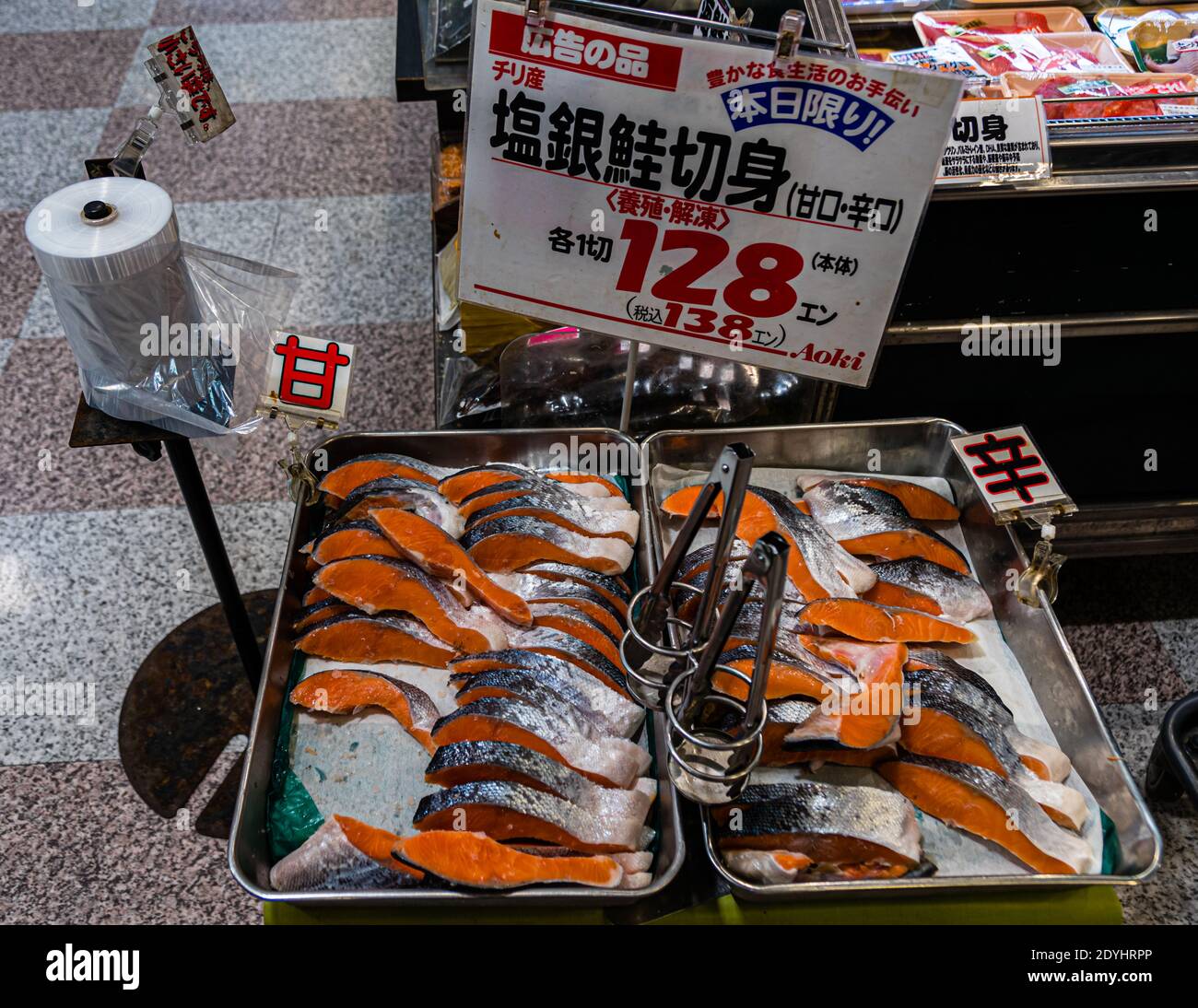 Des morceaux de saumon fileté sont exposés à la vente dans deux bacs métalliques sur un comptoir de poisson dans un supermarché à Nishiizu-Cho, préfecture de Shizuoka, Japon ; un panneau fait la promotion du saumon d'élevage décongelé du Chili comme offre du jour à 128 yens l'unité. Banque D'Images
