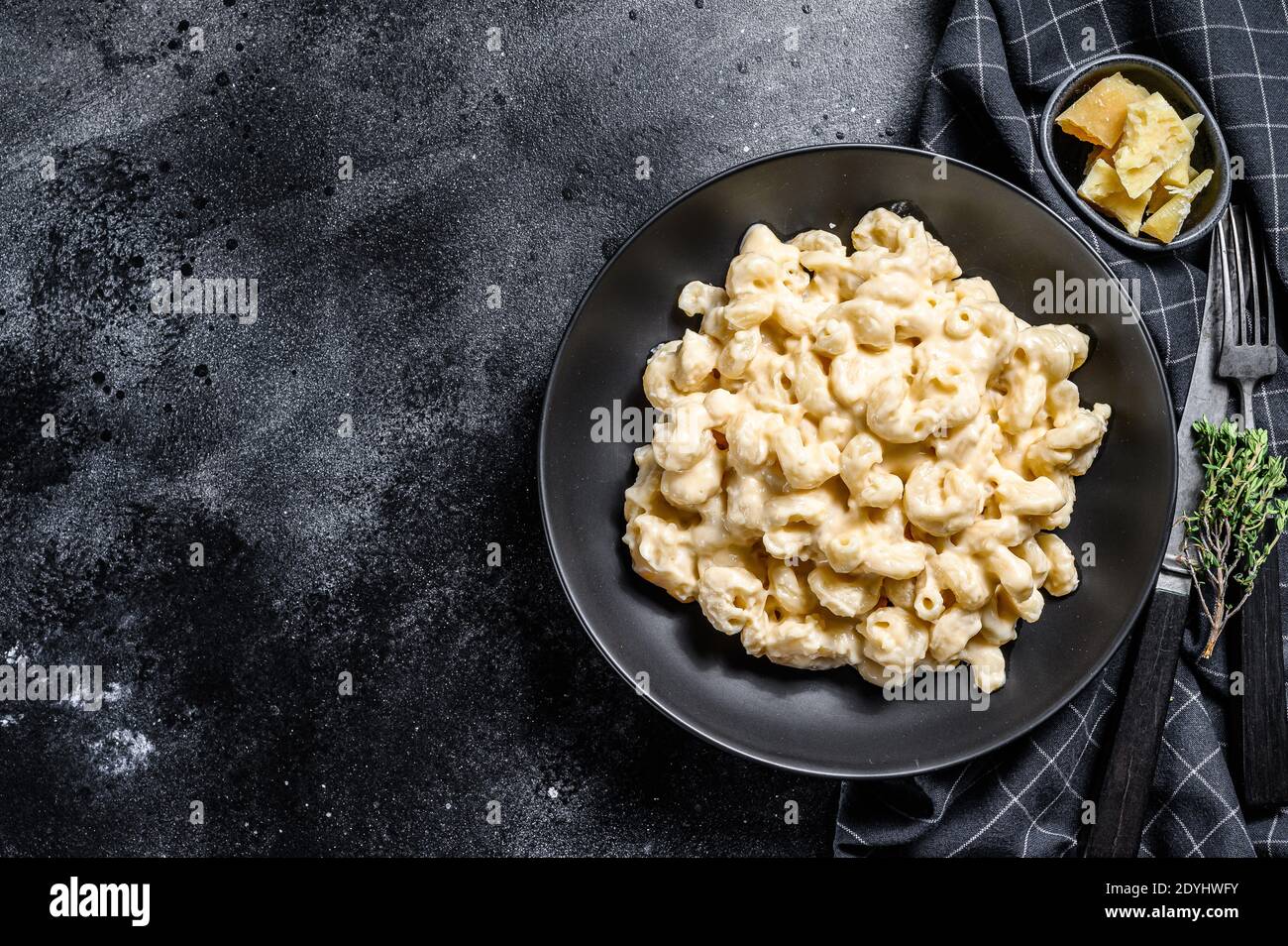 Mac et fromage. Pâtes de macaroni de style américain, sauce cheesy. Arrière-plan en bois noir. Vue de dessus. Copier l'espace Banque D'Images