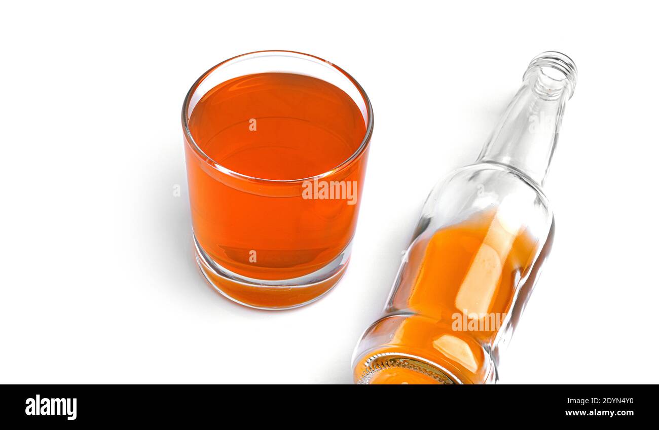 Une bouteille et un verre avec une boisson à l'orange sur fond blanc. Photo de haute qualité Banque D'Images