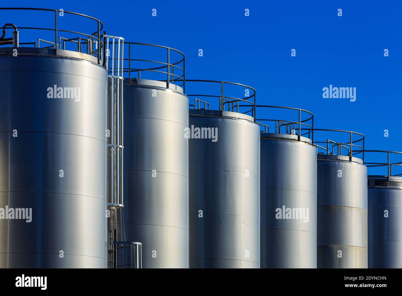 Une rangée de réservoirs de stockage géants en métal étincelant au soleil. Photographié dans une usine laitière Banque D'Images