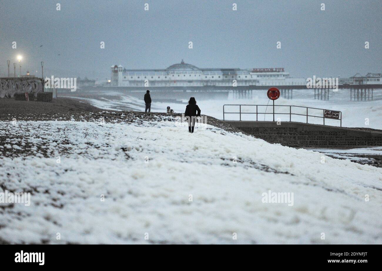 Brighton Royaume-Uni 27 décembre 2020 - UN marcheur se démène à travers la mousse de mer qui a été soufflé sur la plage de Brighton comme Storm Bella batte la Grande-Bretagne aujourd'hui avec de forts vents et de fortes pluies causant des inondations et des dommages dans certaines zones : crédit Simon Dack / Alay Live News Banque D'Images