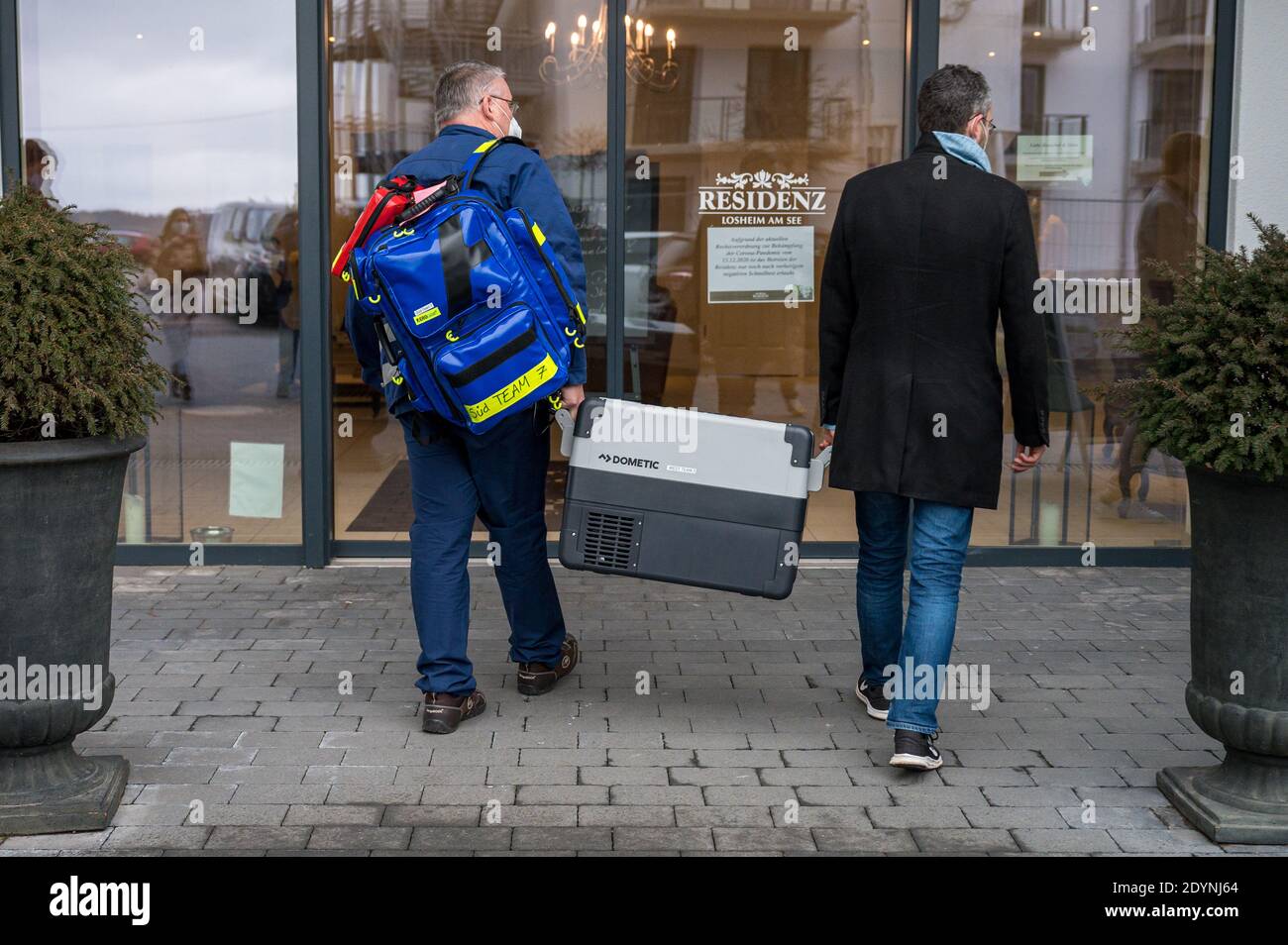 Losheim, Allemagne. 27 décembre 2020. Deux membres de l'équipe de vaccination sont debout avec le vaccin devant l'entrée de la résidence principale de Losheim am See. La vaccination de Corona avec le vaccin Biontech/Pfizer a commencé dimanche en Allemagne. Credit: Oliver Dietze/dpa/Alay Live News Banque D'Images
