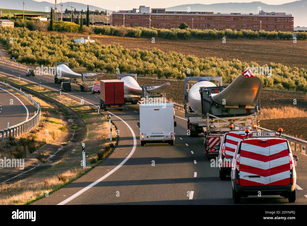 Transport spécial des pales de l'éolienne. Plusieurs camions avec pales d'éolienne circulant sur la route avec des véhicules à balise derrière pour avertir d'autres Banque D'Images