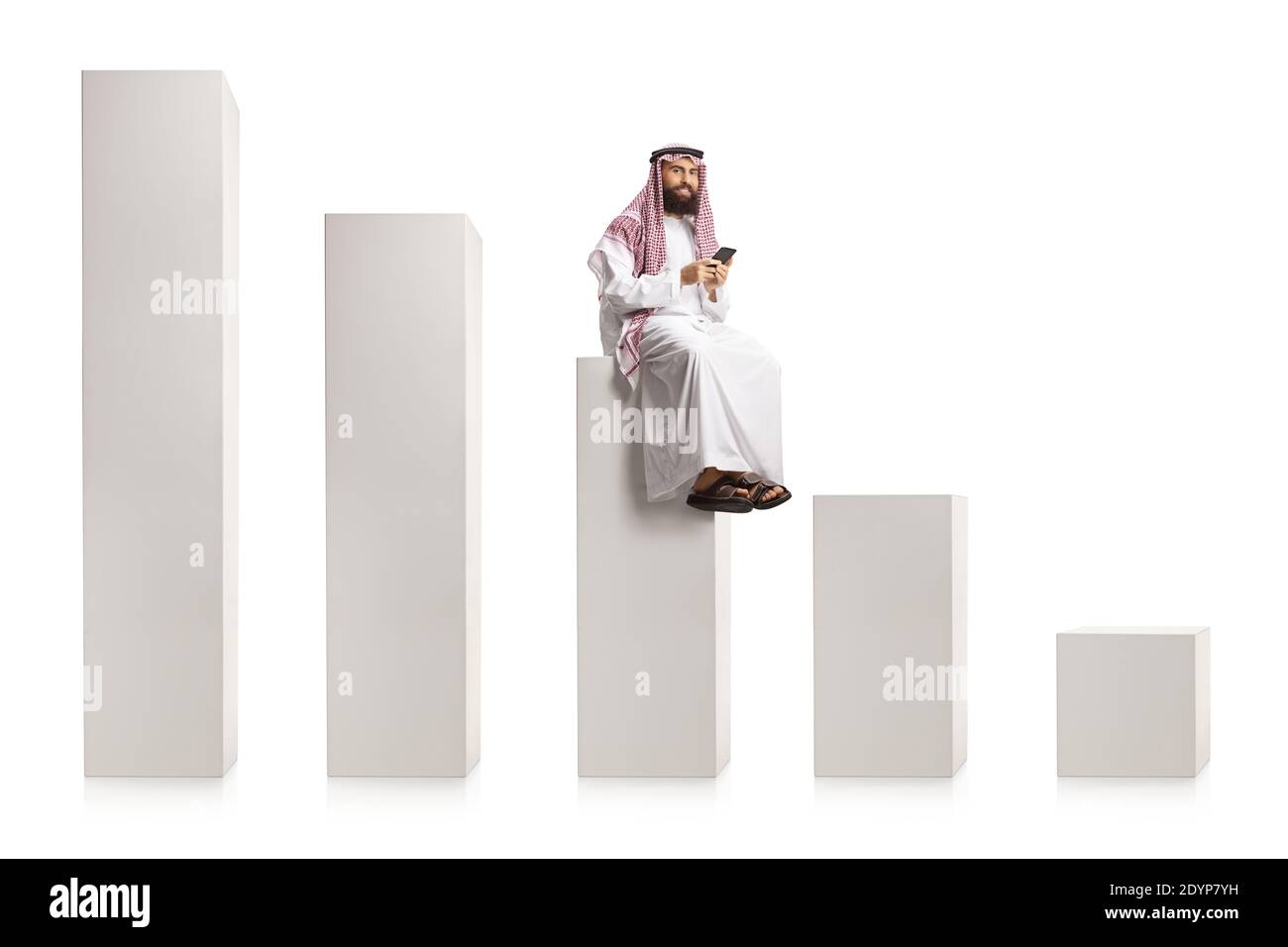 Homme arabe saoudien utilisant un smartphone et assis sur un graphique à colonnes blanc isolé sur fond blanc Banque D'Images