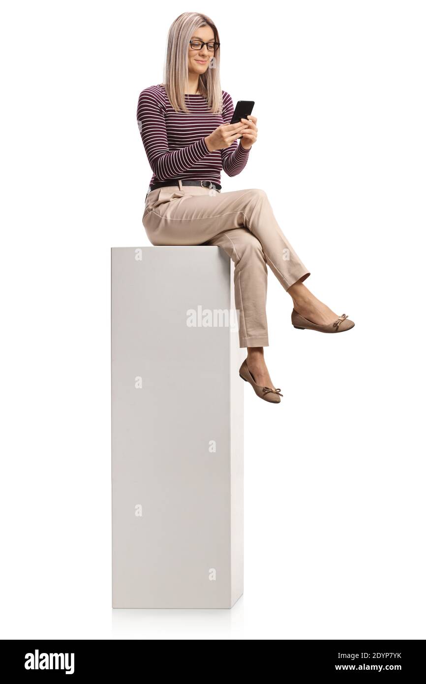 Jeune femme professionnelle avec des lunettes à l'aide d'un smartphone et assis sur une grande colonne blanche isolée sur fond blanc Banque D'Images