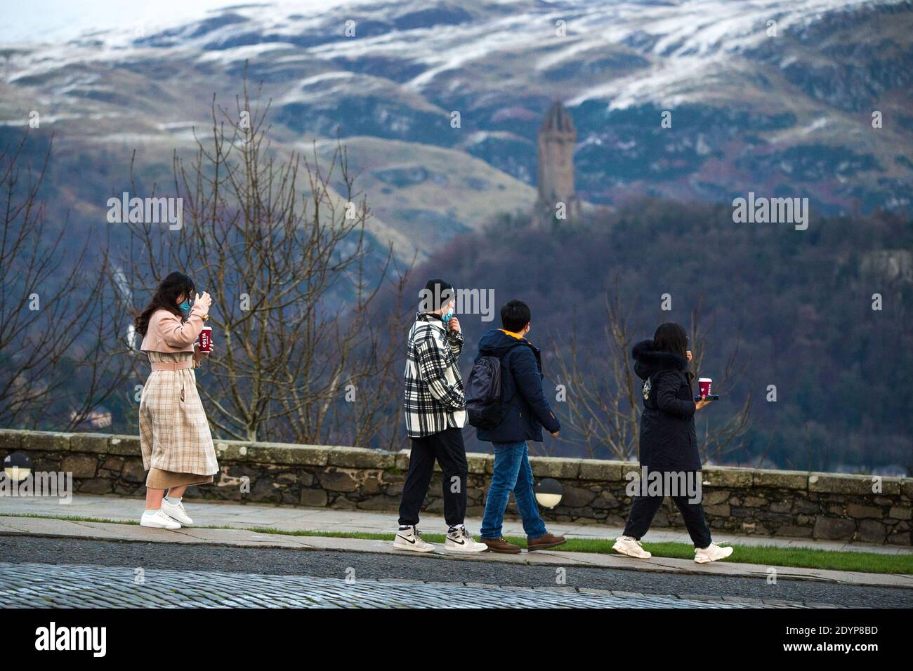 Stirling, Écosse, Royaume-Uni. 27 décembre 2020. Photo : deuxième jour du confinement de la phase 4 festive pour l'Écosse continentale. Un petit groupe de touristes chinois portant des masques de visage regardent sur le Monument Wallace du point de vue du château de Stirling qui offre des vues sur des kilomètres autour. Une petite fenêtre dans le temps émerge de l'avertissement météorologique jaune qui a été émis comme Storm Bella donne la neige chute la nuit laissant une poussière de blanc sur les collines d'Ochill. Crédit : Colin Fisher/Alay Live News Banque D'Images