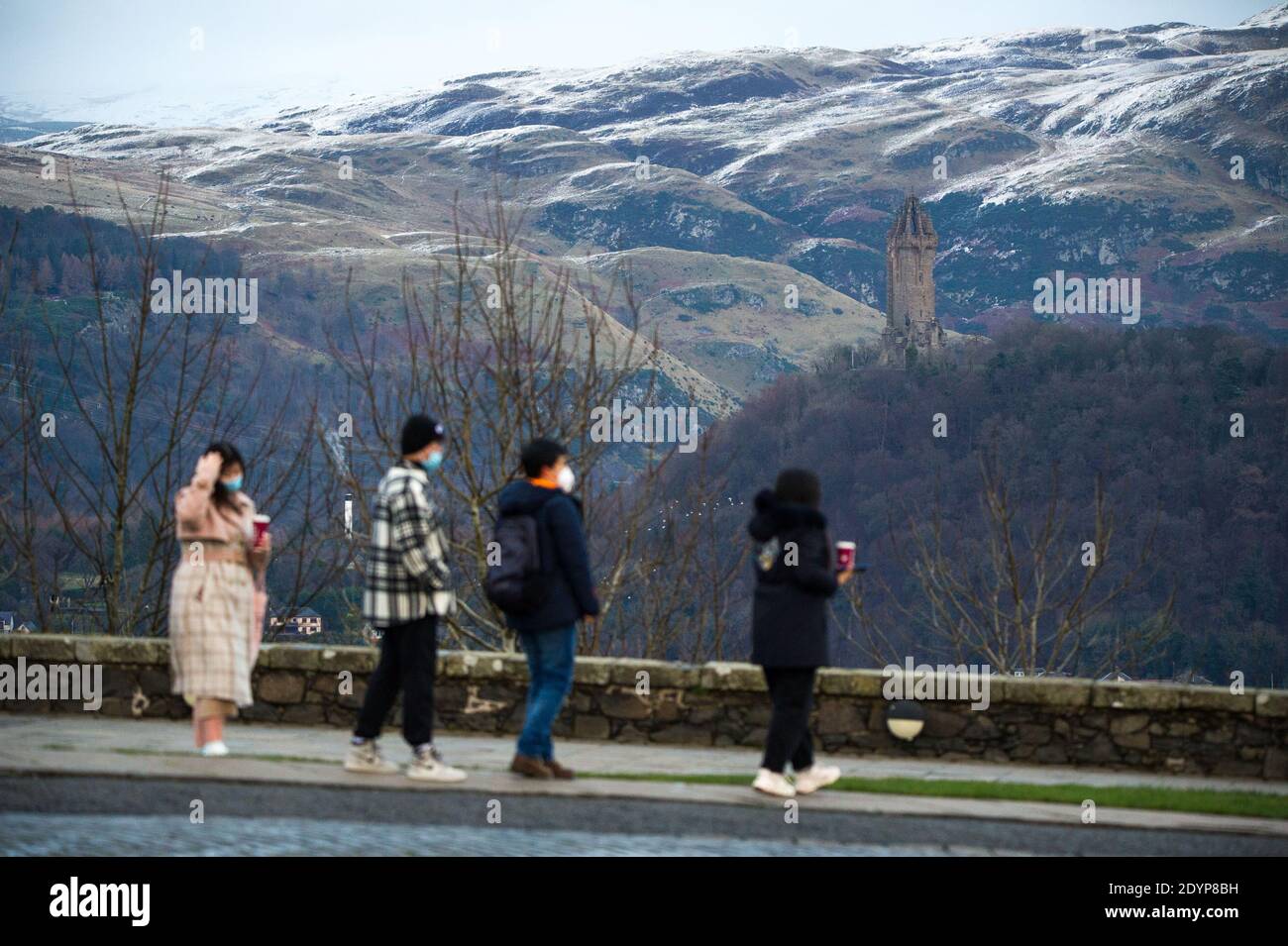 Stirling, Écosse, Royaume-Uni. 27 décembre 2020. Photo : deuxième jour du confinement de la phase 4 festive pour l'Écosse continentale. Un petit groupe de touristes chinois portant des masques de visage regardent sur le Monument Wallace du point de vue du château de Stirling qui offre des vues sur des kilomètres autour. Une petite fenêtre dans le temps émerge de l'avertissement météorologique jaune qui a été émis comme Storm Bella donne la neige chute la nuit laissant une poussière de blanc sur les collines d'Ochill. Crédit : Colin Fisher/Alay Live News Banque D'Images
