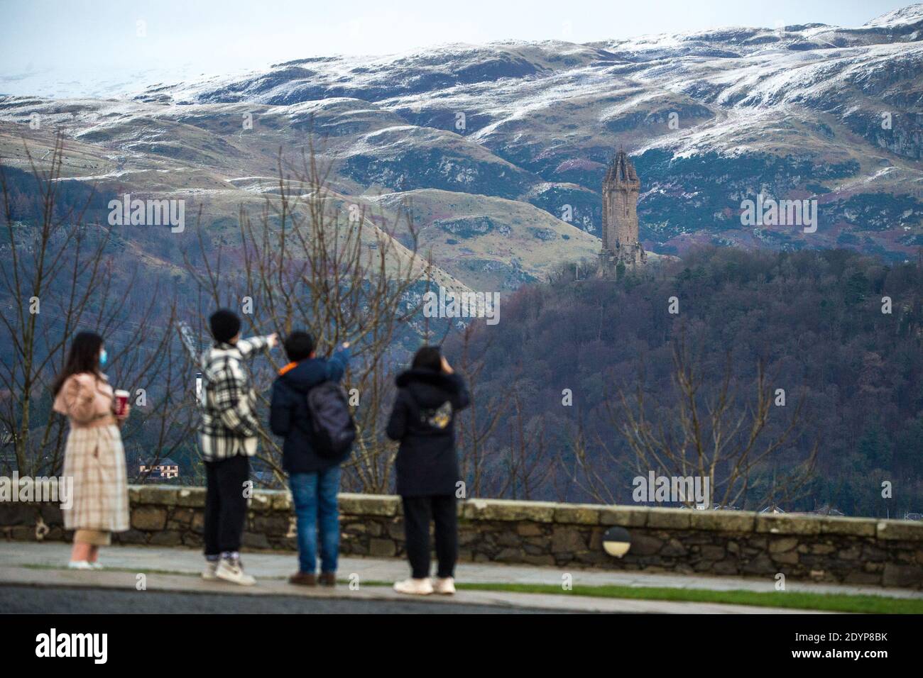 Stirling, Écosse, Royaume-Uni. 27 décembre 2020. Photo : deuxième jour du confinement de la phase 4 festive pour l'Écosse continentale. Un petit groupe de touristes chinois portant des masques de visage regardent sur le Monument Wallace du point de vue du château de Stirling qui offre des vues sur des kilomètres autour. Une petite fenêtre dans le temps émerge de l'avertissement météorologique jaune qui a été émis comme Storm Bella donne la neige chute la nuit laissant une poussière de blanc sur les collines d'Ochill. Crédit : Colin Fisher/Alay Live News Banque D'Images