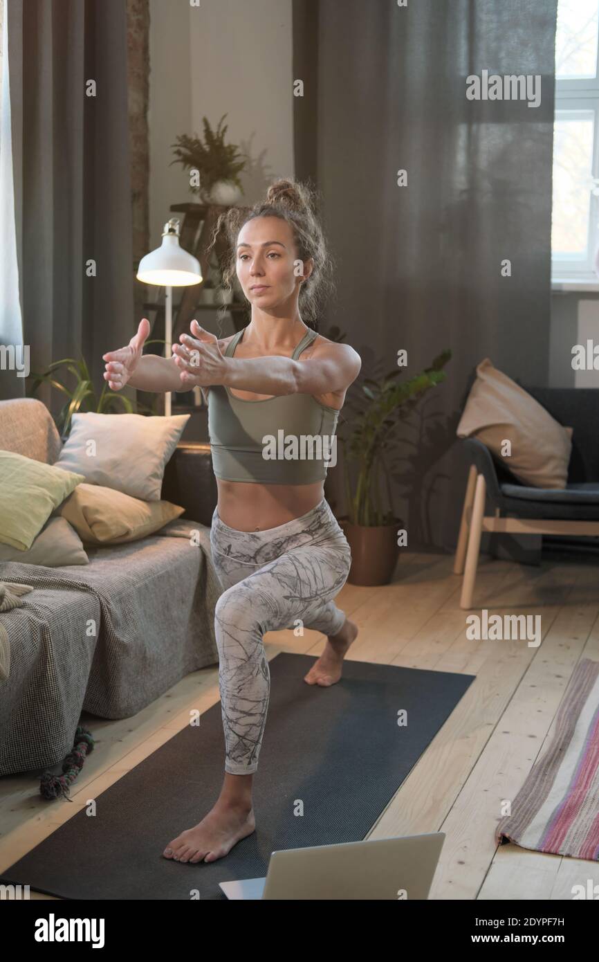 Jeune femme faisant des exercices de sport dans le salon pendant verrouillage Banque D'Images