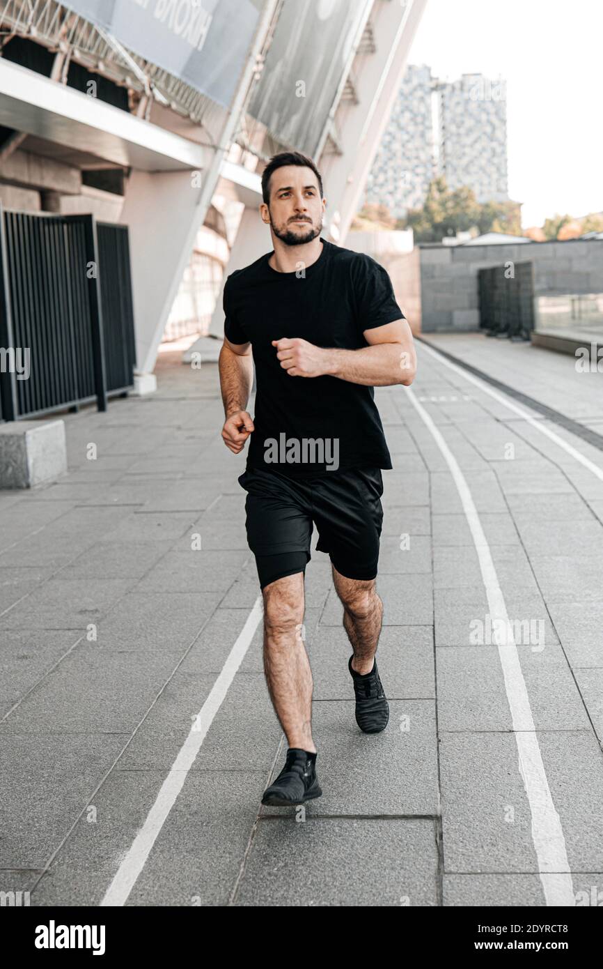 Un homme sportif qui fait du jogging dans la ville. Un mode de vie sain.  Homme en train de courir. Style de vie urbain. Vie active. Fitness en plein  air. Vêtements de