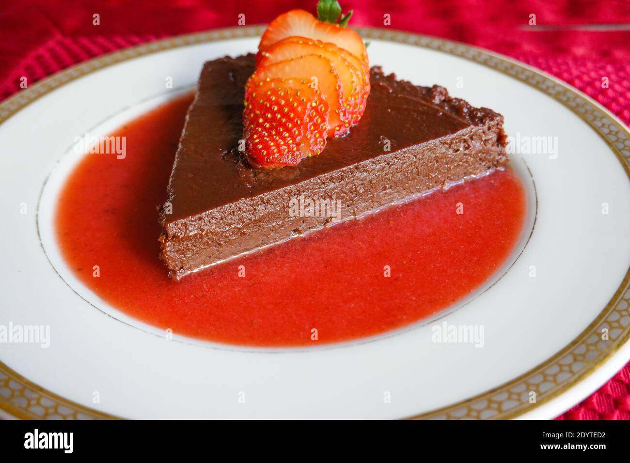 Terrine de chocolat maison plaquée avec une sauce fraisier fraîche avec une fraise fraîche en