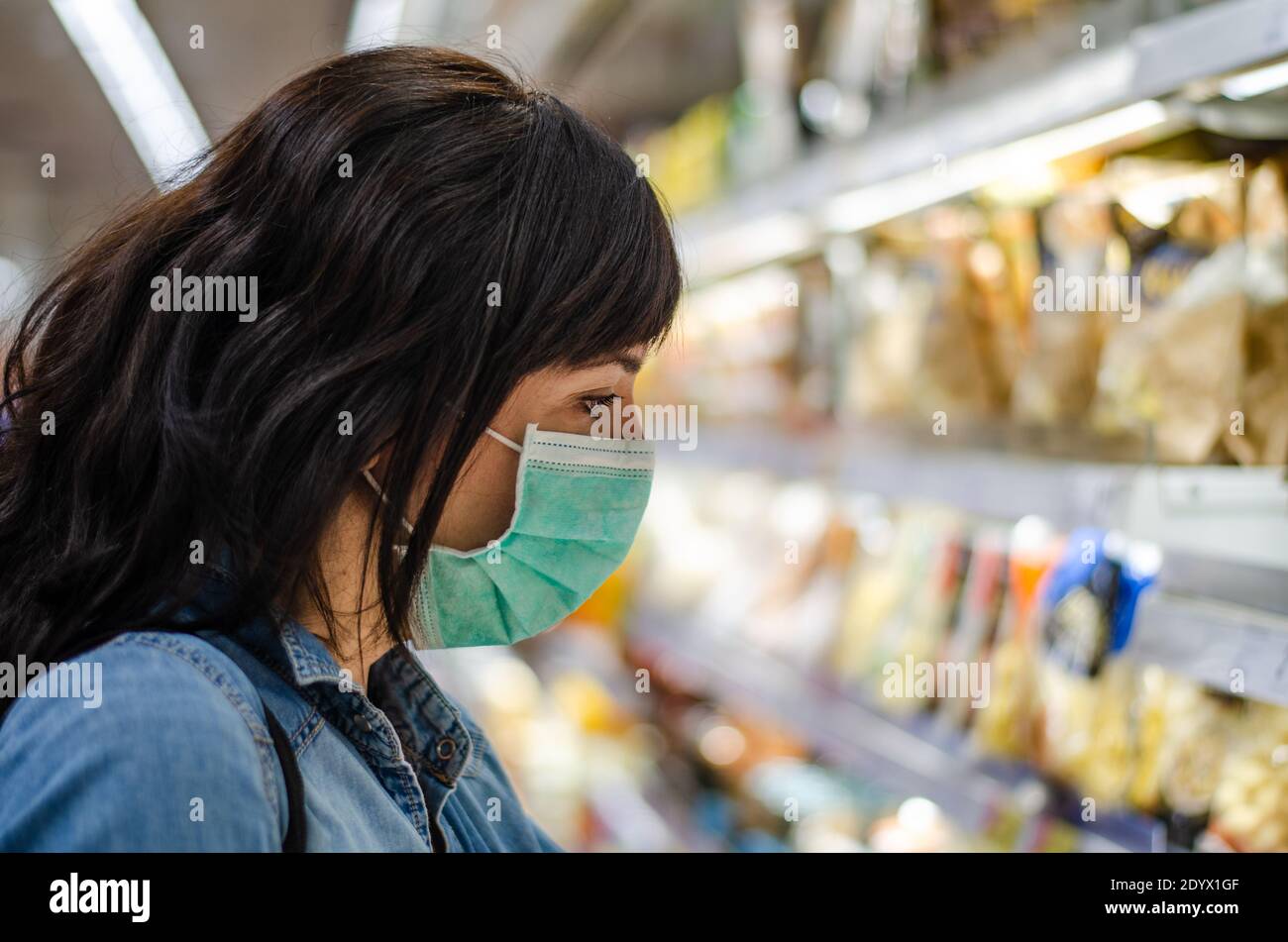 Femme magasiner avec un masque vert dans un supermarché Banque D'Images