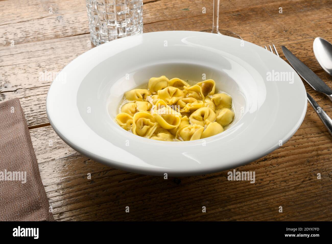 Bol de tortellini ou de pâtes cappellettis dans un bouillon de l' Emilia Romagna région de l'Italie servi dans un blanc élégant plat à la table Banque D'Images