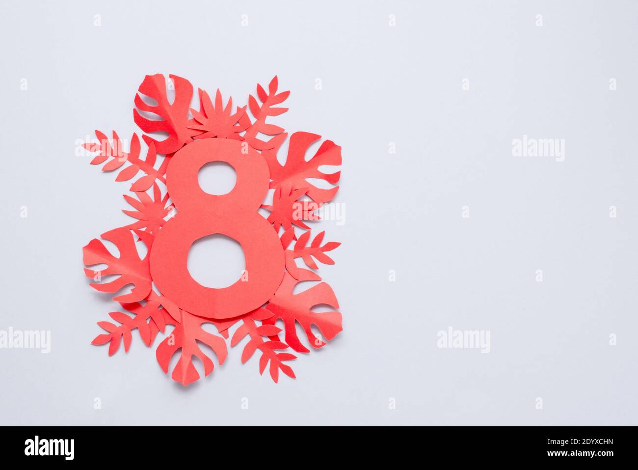 Carte de la fête des femmes du 8 mars avec fleurs et feuilles en papier rouge sur fond gris. Couper à partir du papier. Banque D'Images