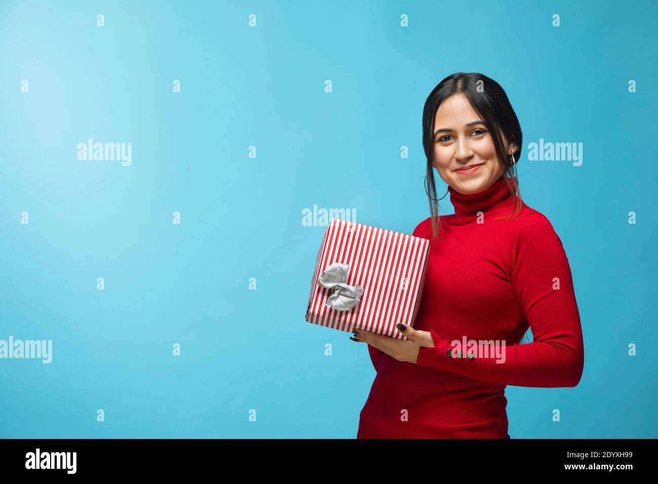 Portrait d'une jeune femme portant un sweat-shirt rouge et tenant un cadeau boîte en main Banque D'Images