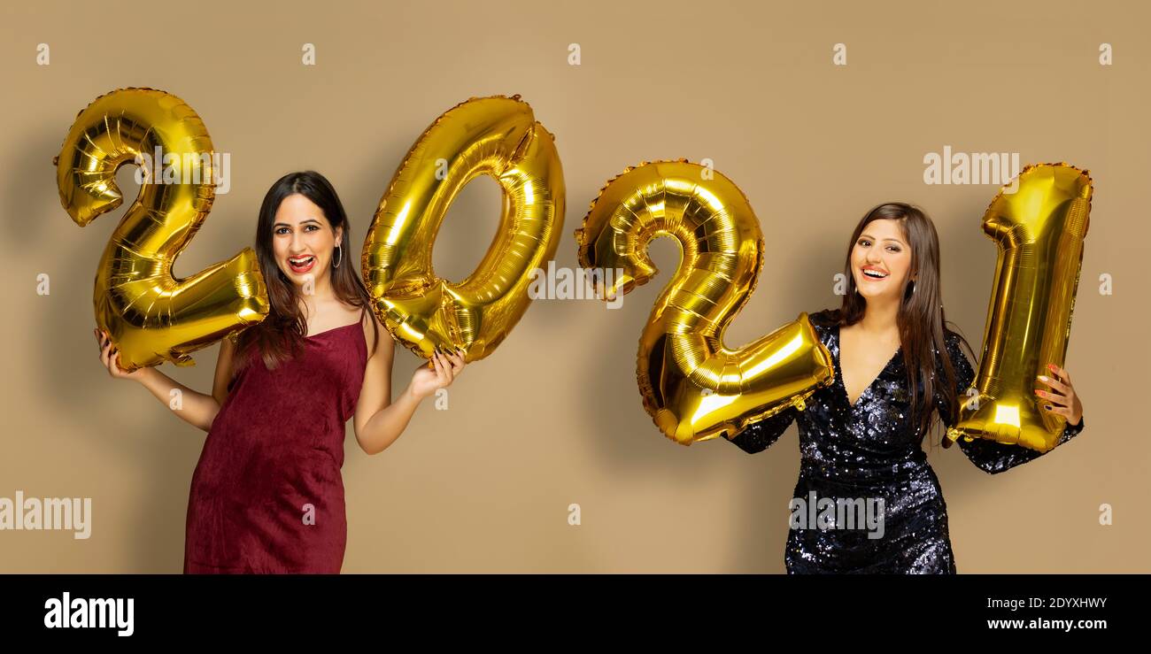Jeunes femmes tenant 2021 ballons d'or au cours d'une nouvelle année fête Banque D'Images