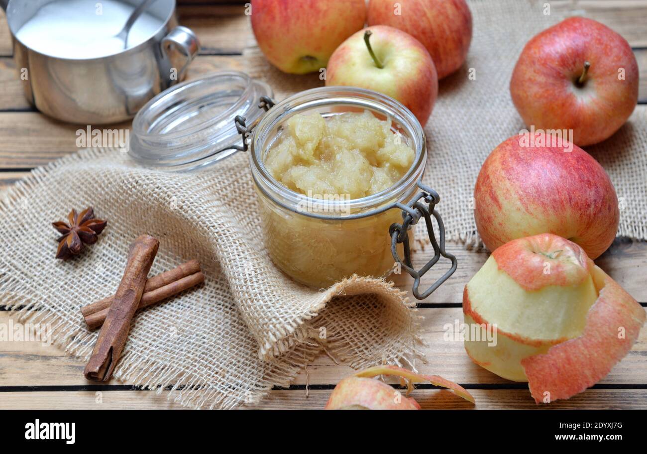 compote maison dans un pot en verre avec des pommes rouges et épices sur une table en bois Banque D'Images